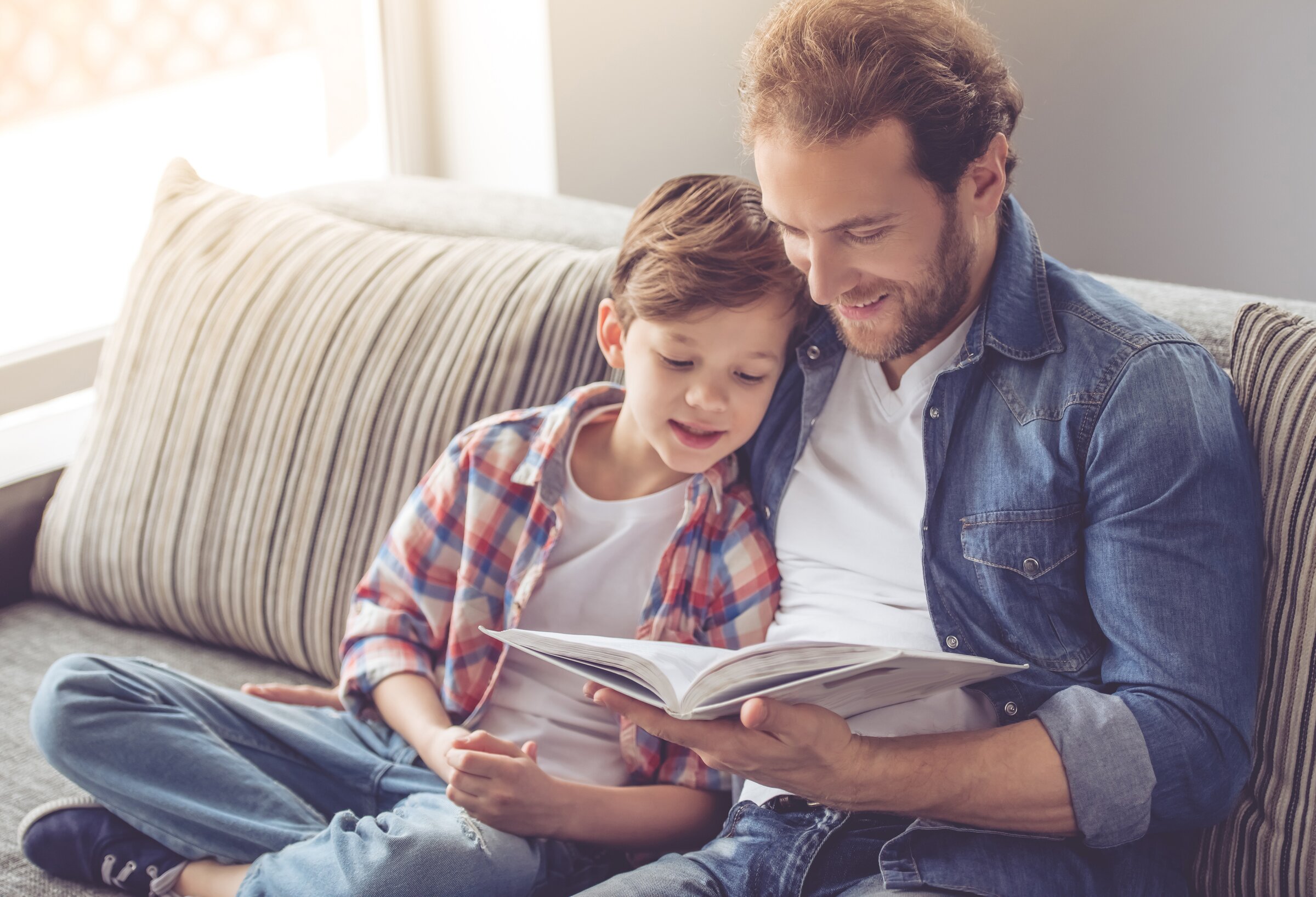 Dad and son on couch reading dad and son connected while reading on couch