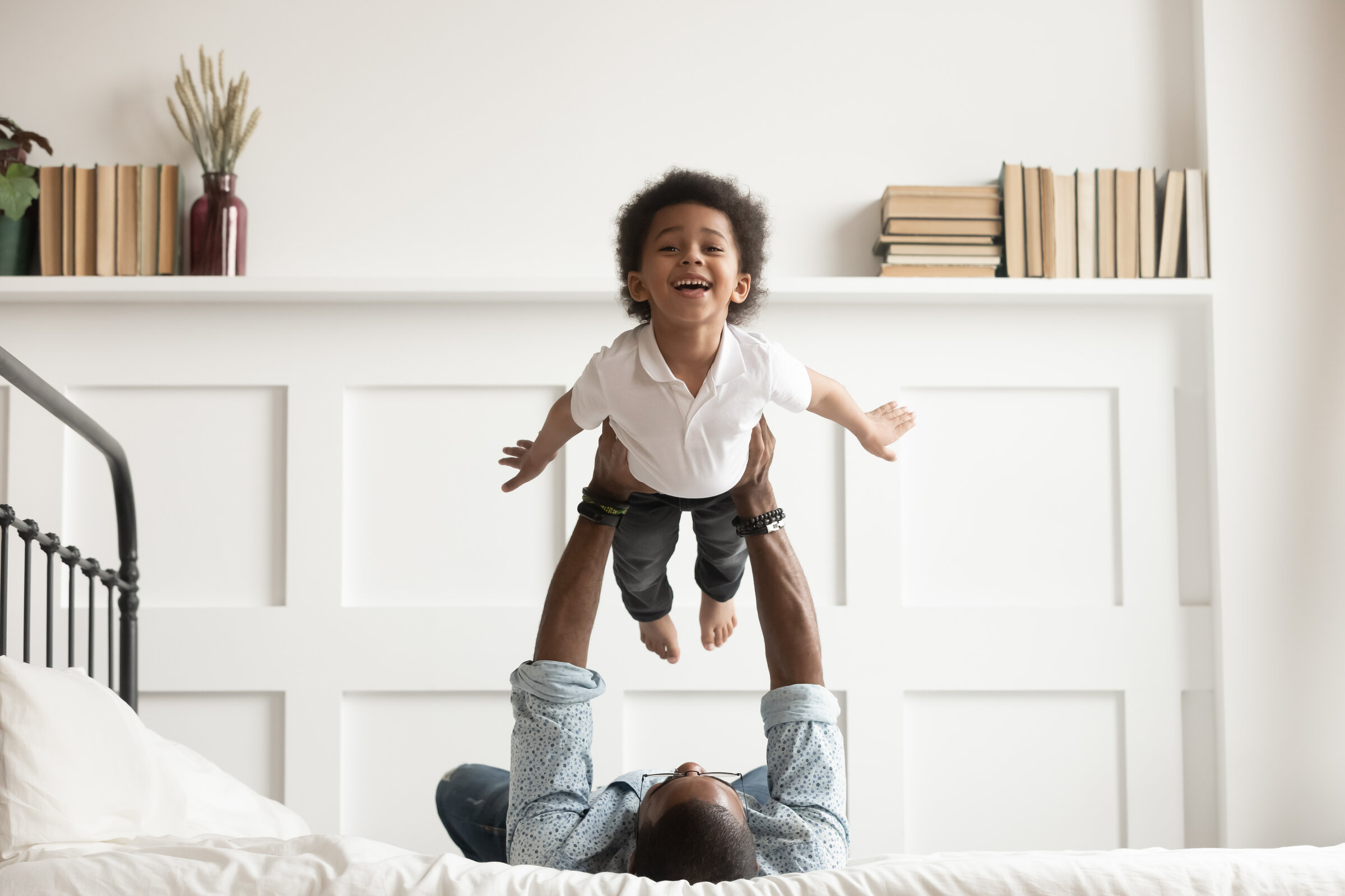 Dad-on-bed-holding-up-toddler